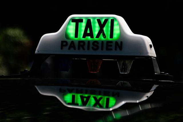 (FILES) This photograph shows a taxi sign and logo in Paris, on August 5, 2025. Taxi drivers in France will be eligible "from October 1, 2026" for a purchase subsidy "of up to Ђ5,500 for an electric vehicle", France's Transport Minister announced on May 21, 2026, during a government press conference on the economic consequences of the war in the Middle East. (Photo by Julie SEBADELHA / AFP)