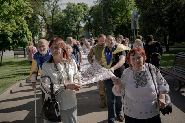 Local residents wearing "vyshyvankas", traditional embroidered Ukrainian shirts, hold an embroidered banner on Vyshyvanka Day in Kharkiv, eastern Ukraine on May 21, 2026, amid the Russian invasion of Ukraine. (Photo by Ivan SAMOILOV / AFP)