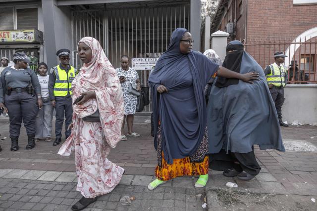 Foreign nationals who say they have no safe place to return to and are appealing for help from the South African government are seen being directed to a bus to be transported from the Diakonia Centre to the Home Affairs offices in Durban on May 21, 2026. The crowd, made up largely of refugees and foreign nationals had been sheltering at the station for up to two days, seeking police protection amid threats and intimidation. Their presence came against the backdrop of sporadic anti-illegal immigration protests that have unsettled parts of South Africa in recent weeks. (Photo by RAJESH JANTILAL / AFP)