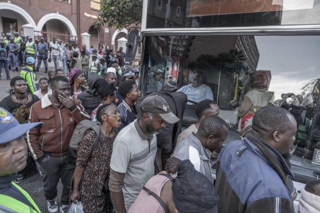 Foreign nationals who say they have no safe place to return to and are appealing for help from the South African government are seen being directed to a bus to be transported from the Diakonia Centre to the Home Affairs offices in Durban on May 21, 2026. The crowd, made up largely of refugees and foreign nationals had been sheltering at the station for up to two days, seeking police protection amid threats and intimidation. Their presence came against the backdrop of sporadic anti-illegal immigration protests that have unsettled parts of South Africa in recent weeks. (Photo by RAJESH JANTILAL / AFP)