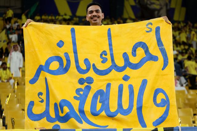 A fan of Al-Nassr holds a banner before the start of the Saudi Pro League football match between Al-Nassr and Damac at the Al-Awwal Park Stadium in Riyadh on May 21, 2026. (Photo by Fayez NURELDINE / AFP)