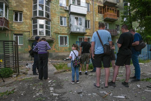 Local residents stand next to debris and a damaged residential building following an air attack in Dnipro on May 21, 2026, amid the Russian invasion of Ukraine. (Photo by Mykola SYNELNYKOV / AFP)