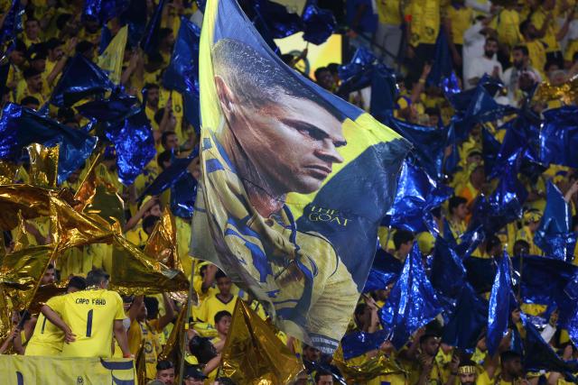 Fans wave a flag with picture of Nassr's Portuguese forward #07 Cristiano Ronaldo before the start of the Saudi Pro League football match between Al-Nassr and Damac at the Al-Awwal Park Stadium in Riyadh on May 21, 2026. (Photo by Fayez NURELDINE / AFP)