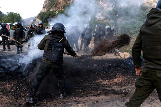 Bolivian police officers clear a blockade on the road between Cochabamba and La Paz during a protest by social movements calling for the resignation of President Rodrigo Paz near Parotani, Bolivia on May 21, 2026. Bolivia's centre-right President Rodrigo Paz announced on May 20 that he will make changes to his cabinet to include social sectors, in an attempt to quell protests demanding his resignation just six months after taking office. (Photo by David FLORES / AFP)