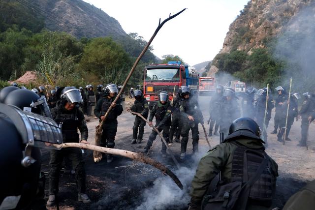 Bolivian police officers clear a blockade on the road between Cochabamba and La Paz during a protest by social movements calling for the resignation of President Rodrigo Paz near Parotani, Bolivia on May 21, 2026. Bolivia's centre-right President Rodrigo Paz announced on May 20 that he will make changes to his cabinet to include social sectors, in an attempt to quell protests demanding his resignation just six months after taking office. (Photo by David FLORES / AFP)