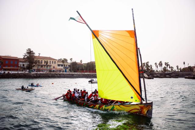 Local officials and members of a Martinican delegation sail on a Martinican yole, a wooden sailboat unique to Martinique, during a commemoration event marking the abolition of slavery and the 50th anniversary of the historic meeting between Leopold Sedar Senghor and Aime Cesaire on Goree Island, Dakar, on May 21, 2026. (Photo by Lisa Coulaud / AFP)