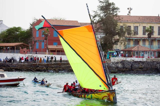 Local officials and members of a Martinican delegation sail on a Martinican yole, a wooden sailboat unique to Martinique, during a commemoration event marking the abolition of slavery and the 50th anniversary of the historic meeting between Leopold Sedar Senghor and Aime Cesaire on Goree Island, Dakar, on May 21, 2026. (Photo by Lisa Coulaud / AFP)