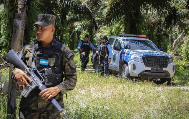 Honduran soldiers and police officers guard the site of a massacre in Trujillo, Honduras on May 21, 2026. Several people were massacred in a town in northern Honduras where rival gangs are fighting for control of palm oil plantations, authorities and residents said on May 20, 2026. (Photo by AFP)