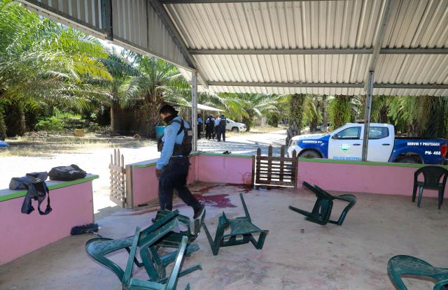 A police officer walks on the site of a massacre in Trujillo, Honduras on May 21, 2026. Several people were massacred in a town in northern Honduras where rival gangs are fighting for control of palm oil plantations, authorities and residents said on May 20, 2026. (Photo by AFP)