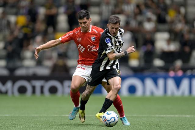Cienciano's Paraguayan defender #13 Claudio Nunez and Atletico Mineiro's midfielder #11 Bernard fight for the ball during the Copa Sudamericana group stage football match between Brazil's Atletico Mineiro and Peru's Cienciano at Arena MRV stadium in Belo Horizonte, Minas Gerais state, Brazil on May 21, 2026. (Photo by DOUGLAS MAGNO / AFP)