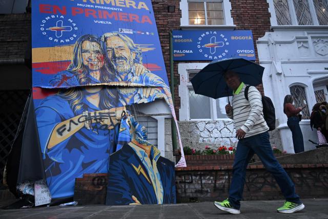 A man walks past a vandalised banner depicting Colombia's presidential candidate Paloma Valencia and vice-presidential candidate Juan Daniel Oviedo, from the Centro Democratico party, outside the campaign headquarters in Bogota on May 21, 2026. Colombia will hold presidential elections on May 31. (Photo by Raul ARBOLEDA / AFP)
