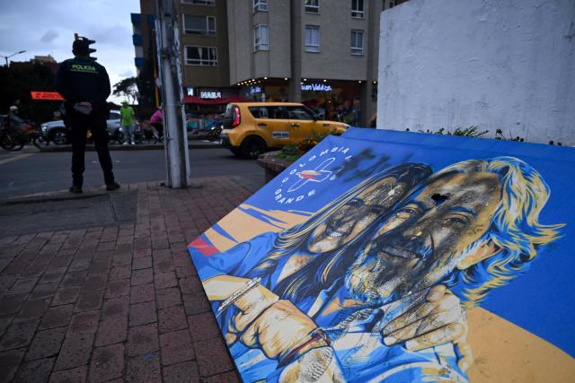 A Colombian police officer stands next to a vandalised banner depicting Colombia's presidential candidate Paloma Valencia and vice-presidential candidate Juan Daniel Oviedo, from the Centro Democratico party, outside the campaign headquarters in Bogota on May 21, 2026. Colombia will hold presidential elections on May 31. (Photo by Raul ARBOLEDA / AFP)