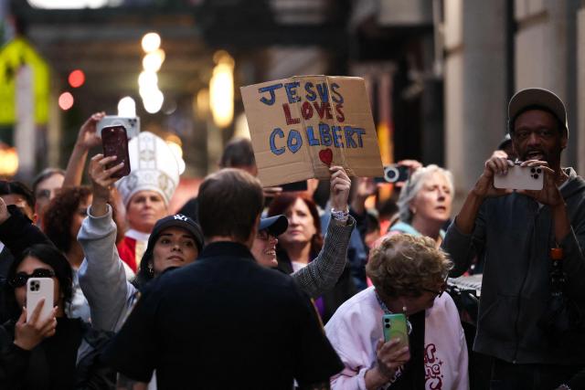 People wait in hopes to see Stephen Colbert outside the Ed Sullivan Theater after the taping of the final episode of the "The Late Show" in New York, on May 21, 2026. "The Late Show" frontman Stephen Colbert will host the final edition of the 33-year-old US cultural institution on May 21, after it was cancelled by CBS as the network courted President Donald Trump. The show, which Colbert has hosted since 2015, was axed after he mocked the broadcaster for a $16 million settlement with Trump for allegedly "maliciously" editing an interview with his Democratic election rival Kamala Harris. (Photo by CHARLY TRIBALLEAU / AFP)