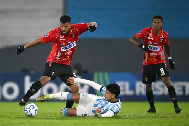 Caracas' defender #04 Jesus Quintero (L) and Racing's forward #58 Tomas Perez (C) fight for the ball during the Copa Sudamericana group stage football match between Argentina's Racing Club and Venezuela's Caracas FC at Presidente Peron 'El Cilindro' stadium in Avellaneda, Buenos Aires province, Argentina on May 21, 2026. (Photo by Luis ROBAYO / AFP)