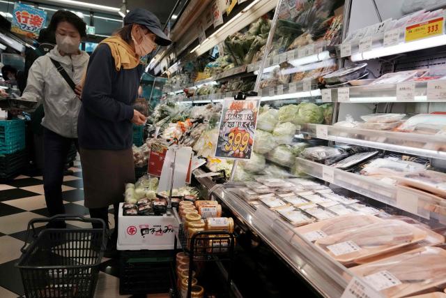 Customers look at fresh food in a supermarket in Tokyo on May 22, 2026. Japan's core inflation slowed to 1.4 percent in April, government data showed Friday, as Prime Minister Sanae Takaichi considers further measures to drive down costs linked to the Middle East war. (Photo by Kazuhiro NOGI / AFP)
