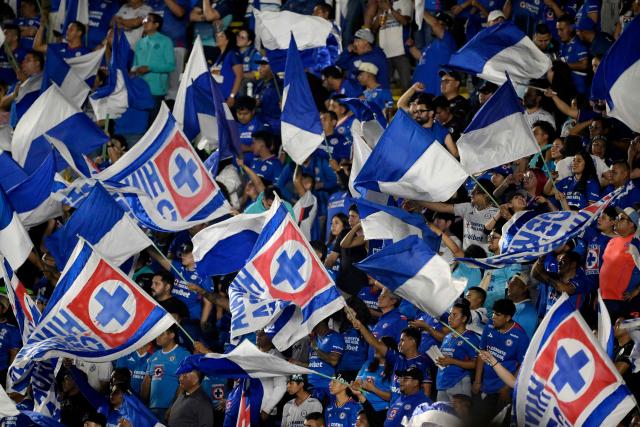 Fans of Cruz Azul wave flags as they cheer for their team during the Liga MX Clausura final first-leg football match between Cruz Azul and Pumas at the Ciudad de los Deportes Stadium in Mexico City on May 21, 2026. (Photo by Alfredo ESTRELLA / AFP)