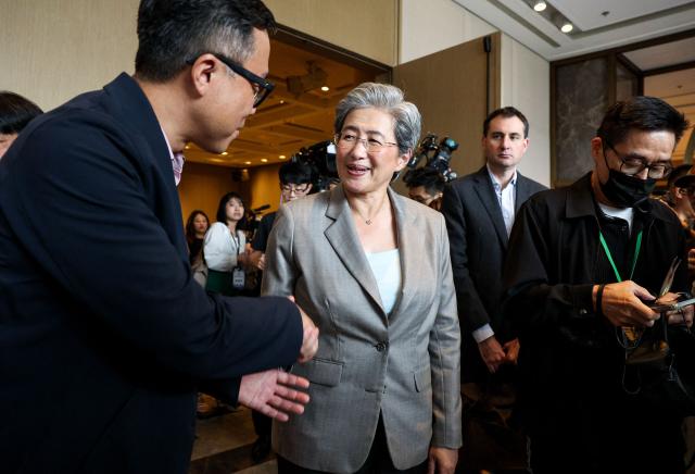Advanced Micro Devices (AMD) CEO Lisa Su (C) shakes hands with a supporter after leaving the forum at Taipei Marriott Hotel in Taipei on May 22, 2026. AMD, a US maker of artificial intelligence processors and a rival to the world's most valuable company Nvidia, announced an investment of more than 10 billion USD into Taiwan's chip industry. (Photo by I-Hwa Cheng / AFP)