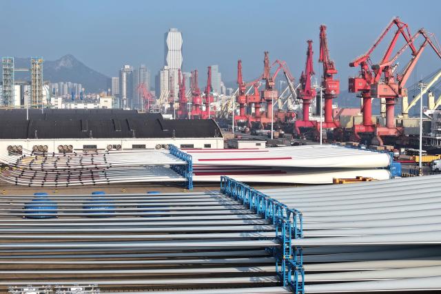 Wind turbine blades made by Goldwind and Vensys are seen on a dock as they are prepared for export at the port in Lianyungang, in China’s eastern Jiangsu province on May 22, 2026. (Photo by CN-STR / AFP) / China OUT