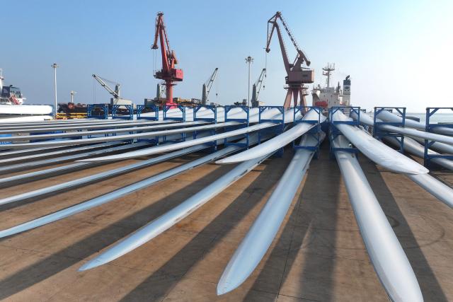 Wind turbine blades made by Goldwind and Vensys are seen on a dock as they are prepared for export at the port in Lianyungang, in China’s eastern Jiangsu province on May 22, 2026. (Photo by CN-STR / AFP) / China OUT