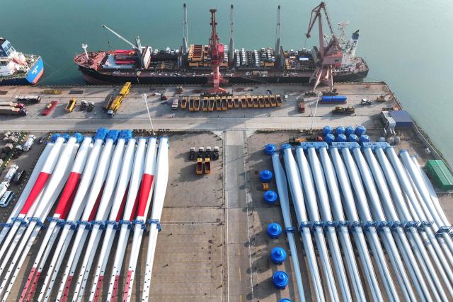 Wind turbine blades made by Goldwind and Vensys are seen on a dock as they are prepared for export at the port in Lianyungang, in China’s eastern Jiangsu province on May 22, 2026. (Photo by CN-STR / AFP) / China OUT