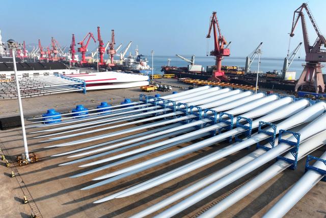 Wind turbine blades made by Goldwind and Vensys are seen on a dock as they are prepared for export at the port in Lianyungang, in China’s eastern Jiangsu province on May 22, 2026. (Photo by CN-STR / AFP) / China OUT