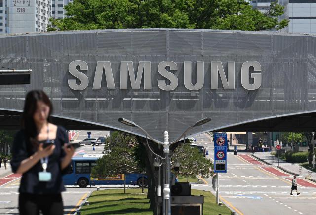 The logo of Samsung Electronics is seen on a gate at the company's headquarters in Suwon on May 22, 2026. Samsung labour union members will begin voting on May 22, on a tentative wage deal that could deliver hefty bonuses to chip workers and helped avert a major strike at the South Korean tech giant this week. (Photo by Jung Yeon-je / AFP)