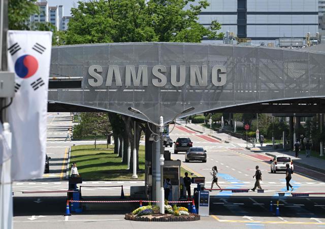 The logo of Samsung Electronics is seen on a gate at the company's headquarters in Suwon on May 22, 2026. Samsung labour union members will begin voting on May 22, on a tentative wage deal that could deliver hefty bonuses to chip workers and helped avert a major strike at the South Korean tech giant this week. (Photo by Jung Yeon-je / AFP)