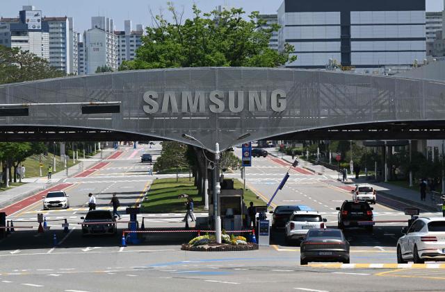 The logo of Samsung Electronics is seen on a gate at the company's headquarters in Suwon on May 22, 2026. Samsung labour union members will begin voting on May 22, on a tentative wage deal that could deliver hefty bonuses to chip workers and helped avert a major strike at the South Korean tech giant this week. (Photo by Jung Yeon-je / AFP)