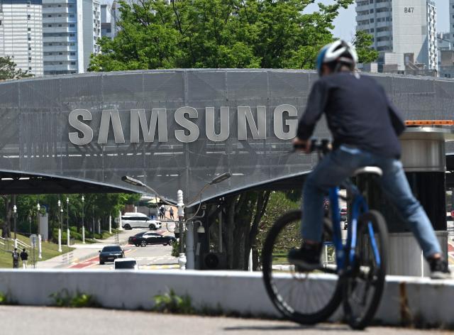 The logo of Samsung Electronics is seen on a gate at the company's headquarters in Suwon on May 22, 2026. Samsung labour union members will begin voting on May 22, on a tentative wage deal that could deliver hefty bonuses to chip workers and helped avert a major strike at the South Korean tech giant this week. (Photo by Jung Yeon-je / AFP)