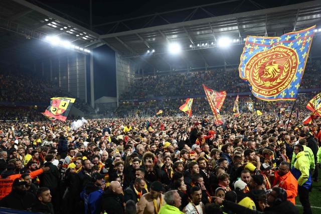 (FILES) Supporters of Lens celebrate on the pitch after their team's victory at the end of the French Cup semi-final football match between and RC Lens and Toulouse FC at the Stade Bollaert-Delelis in Lens, northern France on April 21, 2026. Fervour around RC Lens is building in the Pas-de-Calais mining basin ahead of the French Cup final on May 22, 2026 against Nice, with hopes of lifting this trophy for the first time at the end of a brilliant season. (Photo by Sameer AL-DOUMY / AFP)