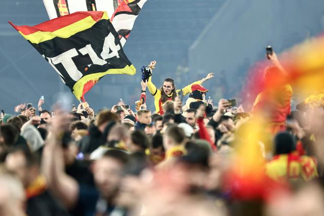 (FILES) Supporters of Lens celebrate on the pitch after their team's victory at the end of the French Cup semi-final football match between and RC Lens and Toulouse FC at the Stade Bollaert-Delelis in Lens, northern France on April 21, 2026. Fervour around RC Lens is building in the Pas-de-Calais mining basin ahead of the French Cup final on May 22, 2026 against Nice, with hopes of lifting this trophy for the first time at the end of a brilliant season. (Photo by Sameer AL-DOUMY / AFP)