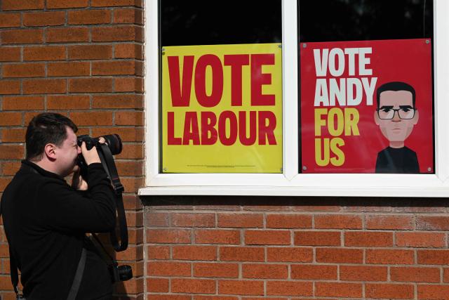 A photographer takes images of posters supporting the Labour Party and Greater Manchester Mayor Andy Burnham in a window, ahead of an event to launch Burnham's by-election campaign in Ashton-in-Makerfield, west of Manchester in north-west England on May 22, 2026. The Makerfield by-election, expected in mid-June at the earliest, may see Burnham return to the government though he would face a tough fight from the poll-topping Reform UK. (Photo by Paul ELLIS / AFP)