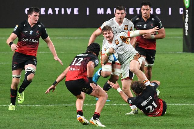 Chiefs' Isaac Hutchinson (C) is tackled during the Super Rugby Pacific match between the Crusaders and Chiefs at One New Zealand Stadium in Christchurch on May 22, 2026. (Photo by Sanka Vidanagama / AFP)
