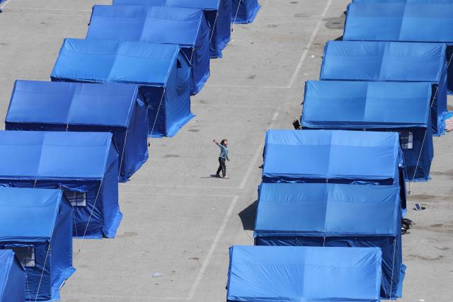 A displaced Lebanese girl plays between blue tents set up by the government for people who fled their homes and villages in Beirut's southern suburbs and southern Lebanon, replacing informal tent settlements in the capital's seafront on May 22, 2026. The government initiative aims to improve living conditions, provide basic services and better manage the growing number of internally displaced people in Beirut following the ongoing crisis. (Photo by Anwar AMRO / AFP)