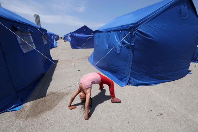 TOPSHOT - A displaced Lebanese girl plays between blue tents set up by the government for people who fled their homes and villages in Beirut's southern suburbs and southern Lebanon, replacing informal tent settlements in the capital's seafront on May 22, 2026. The government initiative aims to improve living conditions, provide basic services and better manage the growing number of internally displaced people in Beirut following the ongoing crisis. (Photo by Anwar AMRO / AFP)