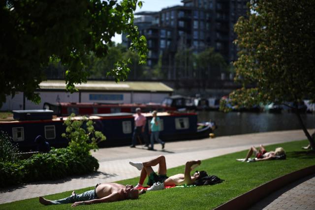People relax in the sunshine beside the Regent's canal in London on May 22, 2026 as temperatures seem set to rise over the long bank holiday weekend. (Photo by Henry NICHOLLS / AFP)