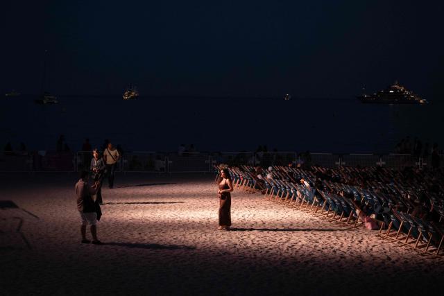 A festival-goer in evening attire poses at the "Cinema de la Plage" on the Boulevard de la Croisette during the 79th edition of the Cannes Film Festival in Cannes, southern France, on May 22, 2026. (Photo by Anna KURTH / AFP)