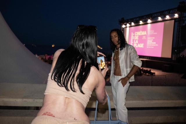 Festival-goers take a photograph near the "Cinema de la Plage" on the Boulevard de la Croisette during the 79th edition of the Cannes Film Festival in Cannes, southern France, on May 22, 2026. (Photo by Anna KURTH / AFP)