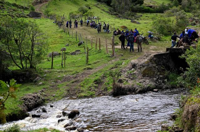 Misak indigenous people walk on a road at the Guambia reserve near Silvia, Cauca department, Colombia on May 22, 2026. A land dispute between two indigenous groups left six people dead and 65 injured in a troubled region of Colombia on May 22, 2026, according to local authorities. (Photo by JOAQUIN SARMIENTO / AFP)