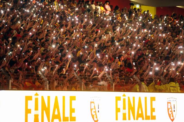 RC Lens supporters hold up their mobile phones with flashlights switched on as they watch the French Cup final football match between RC Lens and OGC Nice on a giant screen at Stade Bollaert in Lens, northern France, on May 22, 2026. (Photo by Francois LO PRESTI / AFP)