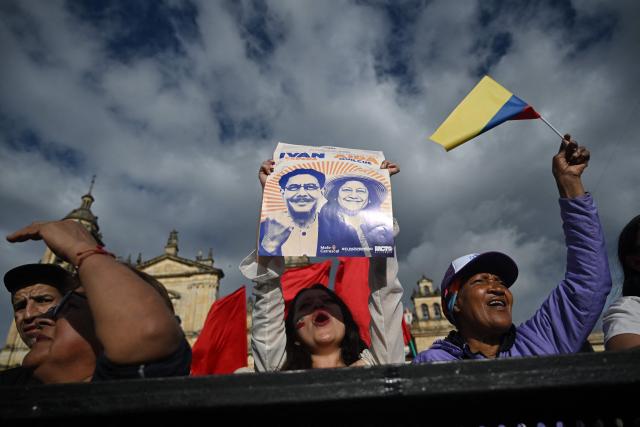 A supporter holds a placard depicting the images of Colombia's presidential candidate Ivan Cepeda and his running mate Aida Quilcue for the Pacto Historico party ahead of the start of a campaign rally at Plaza Bolivar in Bogota on May 22, 2026. Colombia will hold presidential elections on May 31. (Photo by Raul ARBOLEDA / AFP)