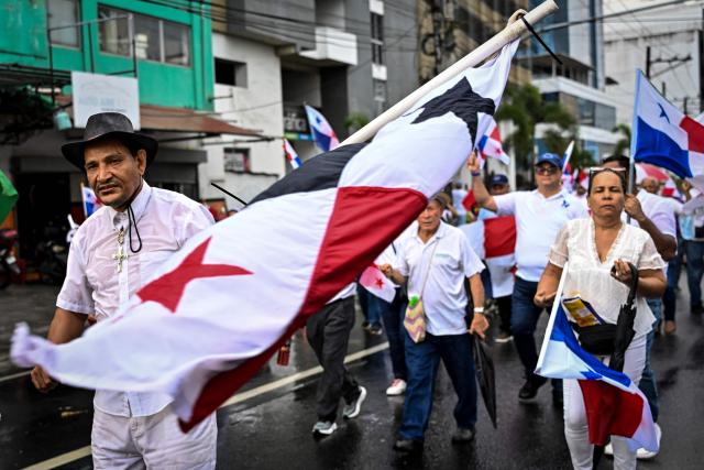 Demonstrators hold national flags as they take part in a march in protest called by workers and members of social organizations against the government of Panamanian President Jose Raul Mulino in Panama City on May 22, 2026. (Photo by MARTIN BERNETTI / AFP)