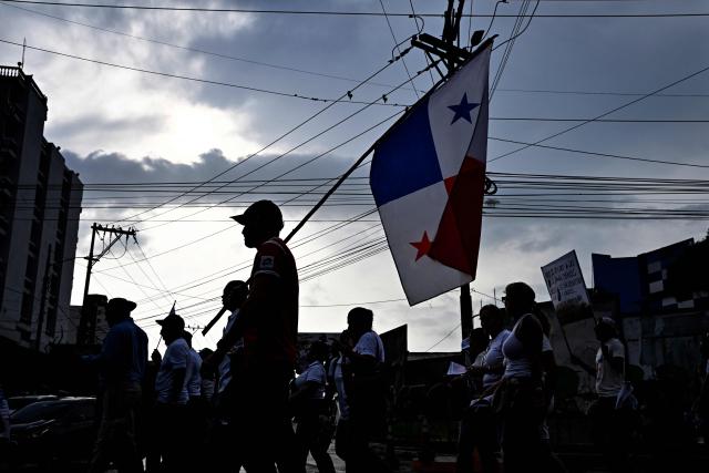 A demonstrator holds a national flag as he takes part in a march in protest called by workers and members of social organizations against the government of Panamanian President Jose Raul Mulino in Panama City on May 22, 2026. (Photo by MARTIN BERNETTI / AFP)