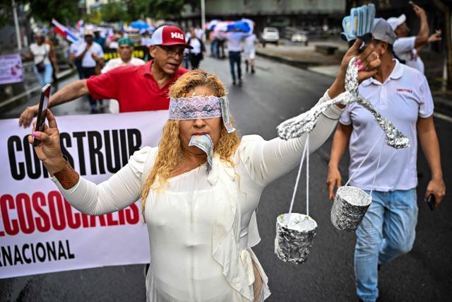 A woman dressed as Lady Justice (Lustitia) performs as she takes part in a march in protest called by workers and members of social organizations against the government of Panamanian President Jose Raul Mulino in Panama City on May 22, 2026. (Photo by MARTIN BERNETTI / AFP)