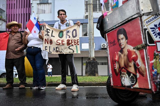 A demonstrator hold a sign that reads ins Spanish "You don't drink gold, but water, you do," as he takes part in a march in protest called by workers and members of social organizations against the government of Panamanian President Jose Raul Mulino in Panama City on May 22, 2026. (Photo by MARTIN BERNETTI / AFP)