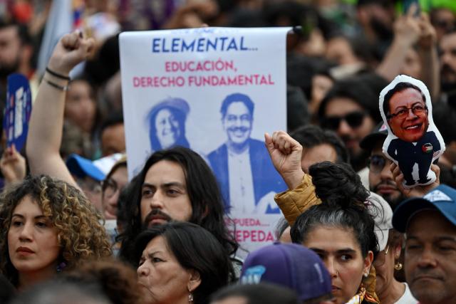 Supporters of Colombia's presidential candidate Ivan Cepeda and his running mate Aida Quilcue for the Pacto Historico party, raise their fist ahead of the start of a campaign rally at Plaza Bolivar in Bogota on May 22, 2026. Colombia will hold presidential elections on May 31. (Photo by Raul ARBOLEDA / AFP)