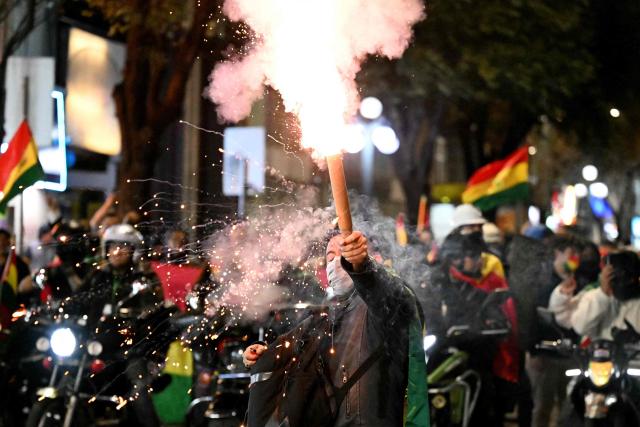 A supporter of the government lights a flare during a demonstration in favor of President Rodrigo Paz and against the blockades in La Paz on May 22, 2026. Thousands of protesters gathered in Bolivia’s political capital on May 22 to demand the resignation of center-right President Rodrigo Paz, during another day of protests that led to clashes with riot police. (Photo by Marvin RECINOS / AFP)