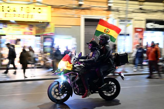 Supporters of the government ride on a motorcycle waving a national flag in a demonstration in favor of President Rodrigo Paz and against the blockades in La Paz on May 22, 2026. Thousands of protesters gathered in Bolivia’s political capital on May 22 to demand the resignation of center-right President Rodrigo Paz, during another day of protests that led to clashes with riot police. (Photo by MARVIN RECINOS / AFP)