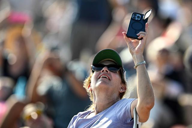 A woman records the launch of SpaceX's Starship 39 rocket from Starbase as people gather in South Padre Island, Texas, on May 22, 2026. Elon Musk's SpaceX on May 22 launched its latest Starship, sending the mammoth rocket soaring into the Texas skies after its initial attempt was scrubbed due to technical issues. The Starship spacecraft and Super Heavy rocket booster appeared to separate as expected, but the company's spokesperson Dan Huot said on the livestream that the booster did not complete a burn necessary to steer itself to a controlled landing, meaning it likely can't make a precision touchdown as hoped. (Photo by RONALDO SCHEMIDT / AFP)