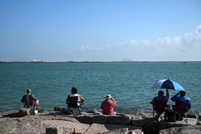 People watch the launch of SpaceX's Starship 39 rocket from Starbase as they gather in South Padre Island, Texas, on May 22, 2026. Elon Musk's SpaceX on May 22 launched its latest Starship, sending the mammoth rocket soaring into the Texas skies after its initial attempt was scrubbed due to technical issues. The Starship spacecraft and Super Heavy rocket booster appeared to separate as expected, but the company's spokesperson Dan Huot said on the livestream that the booster did not complete a burn necessary to steer itself to a controlled landing, meaning it likely can't make a precision touchdown as hoped. (Photo by RONALDO SCHEMIDT / AFP)